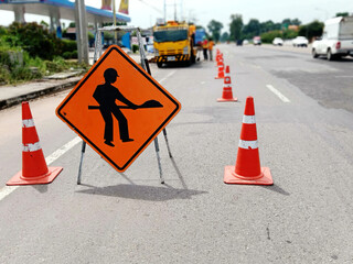 The image is blurred in road maintenance work and there is a warning sign for the construction work.