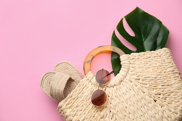 Elegant woman's straw bag with shoes, tropical leaf and sunglasses on pink background, top view