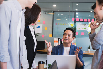 Focus on asian man(boss or manager)standing in group brainstorm meeting in office.Businesspeople discussing with paperwork for business plan,Corporate of modern colleague