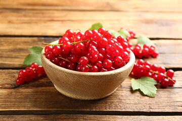 Ripe red currants in bowl on wooden table