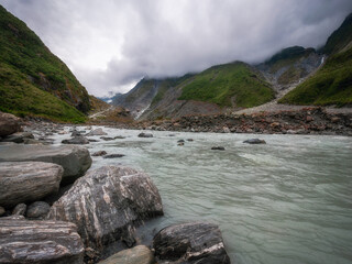Low angle view perspective from the Waiho River water level towards the track to Franz Josef Glacier located in Westland Tai Poutini National Park on the West Coast of New Zealand, South Island. 