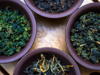 Assortment of Chinese tea in clay bowls on a wooden table