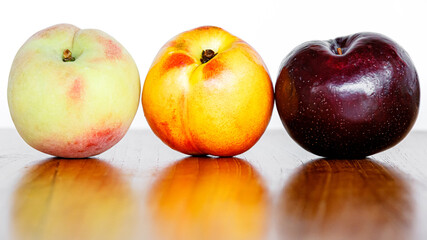 Naklejka na ściany i meble ripe peach plum nectarine fruits on wooden table on white background