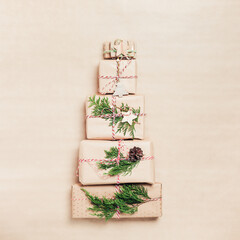 Christmas gift boxes wrapped in craft paper laid out in shape of Christmas tree, top view, copy space