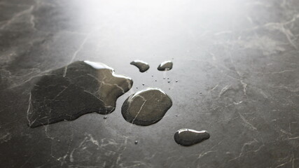Water droplets on a black and white marble table. Spilled water on a table with outside reflection with a copy area. Close focus and select an object