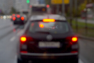  A crack in the windshield from a stone against the background of a car with burning stoplights.
