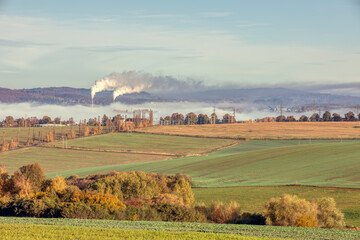 Fototapeta premium industrial cityscape with with smoking factory, ecology and pollution concept. Autumn fall season with mist. Jihlava Kronospan, Czech Republic
