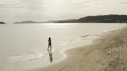 Naklejka premium Beautiful girl walking along the beach, aerial footage from Florianópolis Santa Catarina Brazil