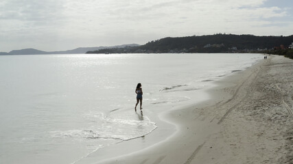 Beautiful girl walking along the beach, aerial footage from Florianópolis Santa Catarina Brazil