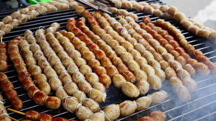 Thai sausages grilled on a grill. Thai street food. Homemade sausages grilled on the stove in the Thai Walking Street Market. Close focus and select an object