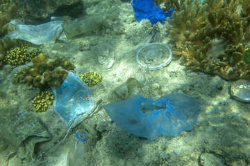 Fototapeta na wymiar Face masks and plastic debris on bottom in Red Sea. Coronavirus COVID-19 is contributing to pollution, as discarded used masks clutter polluting seabed along with plastic trash