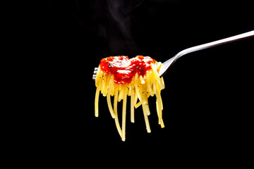 Hot spaghetti on a fork with tomato sauce and steamed seasoning. Pasta on black background