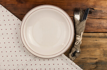 Top view of kitchen cutlery setting with polka dot napkin on grunge restaurant table.