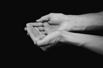 black and white photograph of hands with sand on a black background