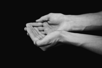 Fototapeta premium black and white photograph of hands with sand on a black background