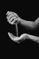 black and white photograph of hands with sand on a black background
