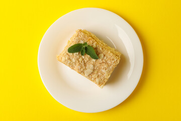 Plate with delicious Napoleon cake on yellow background