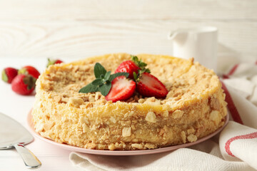 Plate with Napoleon cake with strawberry on white wooden background