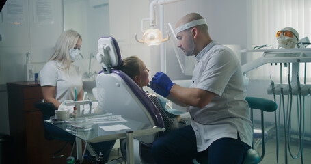 Professional dentist curing teeth of teen girl