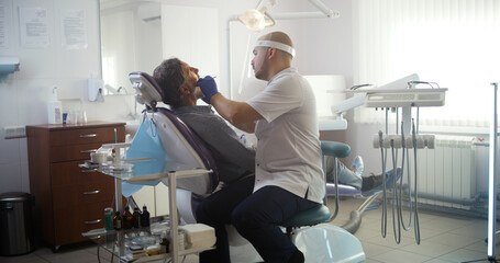Dentist checking up teeth of mature patient