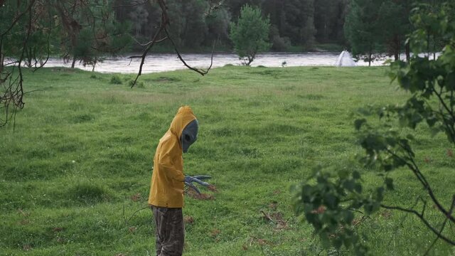 alien in yellow suit in forest near river in nature. goes away looking back, concept of UFO, space, alien.
