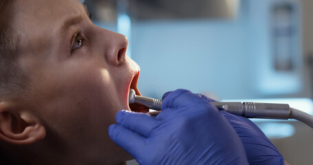 Crop dentist drilling tooth of boy
