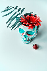 Skull in face mask with vibrant red gerbera daisy flowers. Dia de los Muertos.