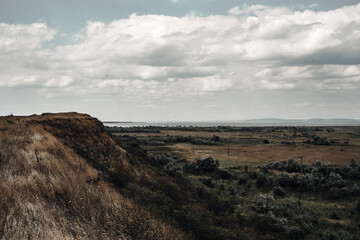 Landscape field, hillside and cloudy sky.