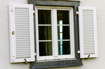 Metal framed window with wood shutters and with white wall