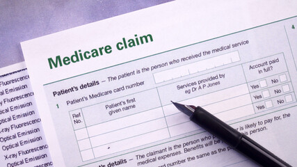 Fototapeta premium Conceptual composition. Pension savings. Three eggs with the inscriptions IRA, 401k, Roth lie in the nest on the x-ray picture next to Medicare claim form and pen. Close-up
