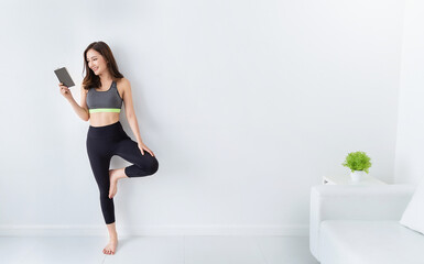 Portrait of young beautiful asian korean woman warm up exercise workout yoga position in white living room. Sporty girl reading book relax at minimal home health care lifestyle knowledge concept