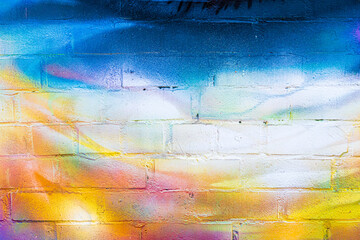 A fragment of colorful graffiti painted on a brick wall. Abstract backdrop for design. - obrazy, fototapety, plakaty