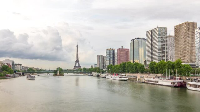 The Eiffel Tower and the Statue of Liberty Timelapse hyperlapse reflected on water with modern buildings and traffic on road. View from Mirabeau bridge before sunset. Paris, France
