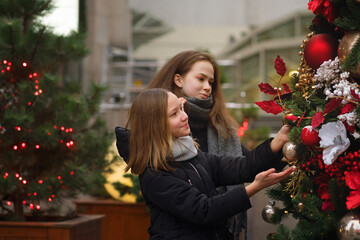 Two female best friends on Christmas Market. Adorable sisters having fun together on traditional Christmas fair. Winter time with family. Girls enjoying the scenery and atmosphere on Xmas market.