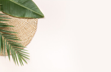 Round wicker stand and palm leaves on pink background. Fltlay style concept with text place