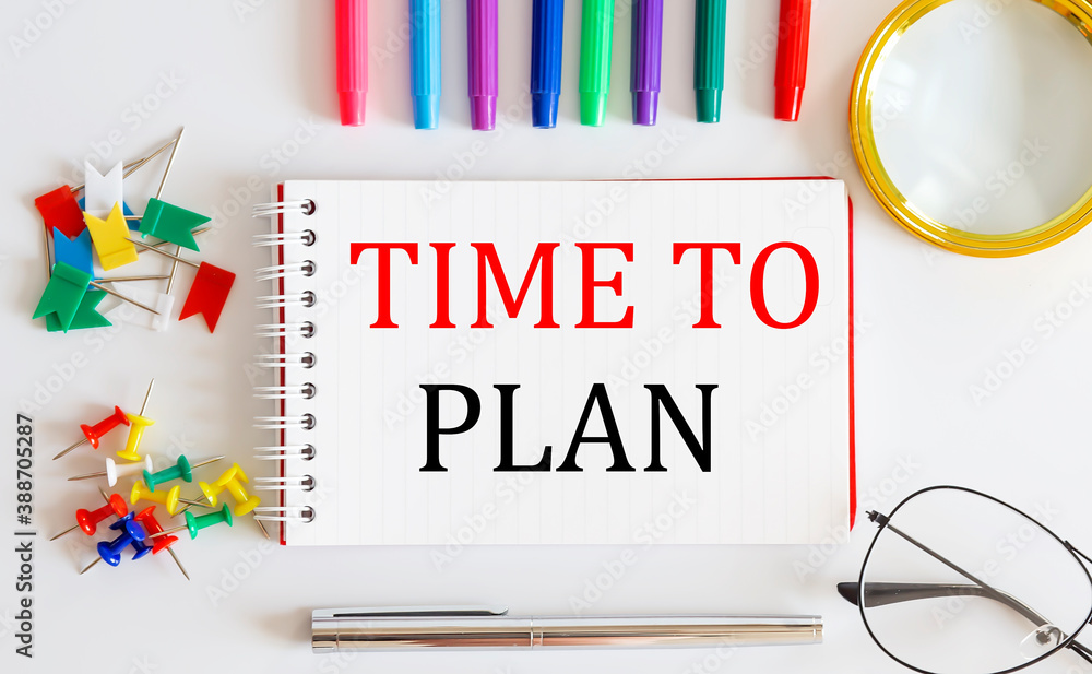 Aufkleber notebook with time to plan word with office tools on the white table.