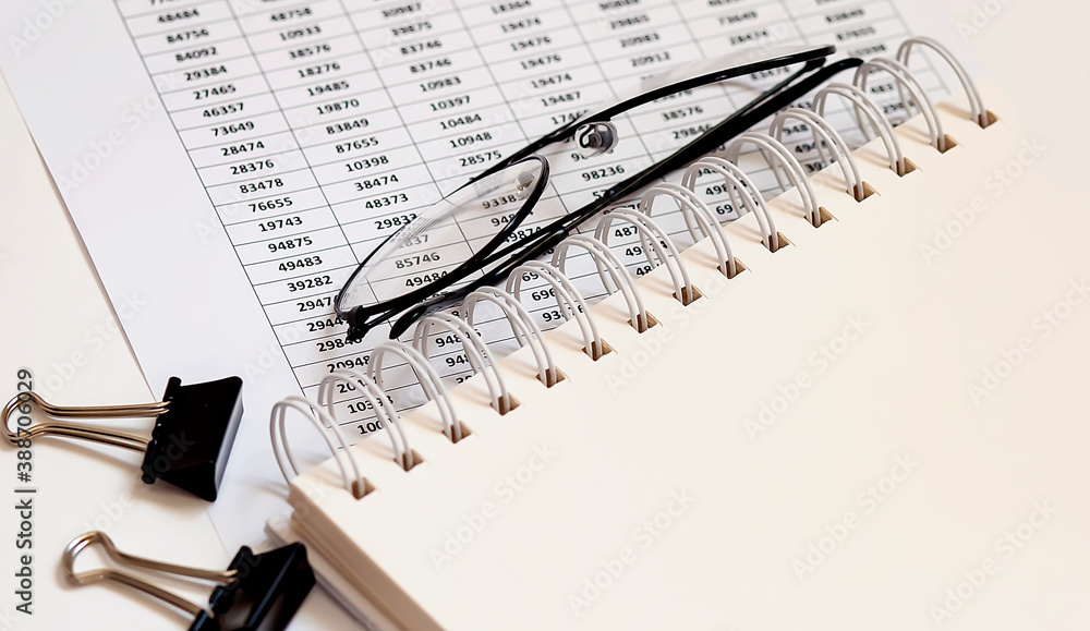 Poster office desk with financial papers, charts,notepad and glasses. empty notepad page for text. a top vi