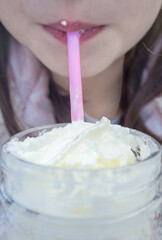 Little girl drinking milkshake through a pink straw