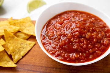 Homemade Tomato Salsa and Nachos on a rustic wooden board, low angle view. Close-up.