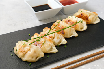 Japanese dumplings Gyoza with pork meat and vegetables on black plate snack with soy sauce. Asian cuisine. typical food Japanese Chinese Korean. delivery takeaway takeout coronavirus food