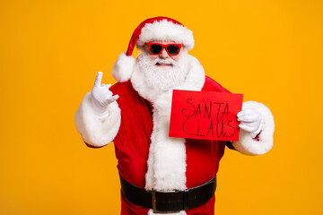 Portrait of his he nice attractive cheerful bad Santa holding in hands red board placard showing...