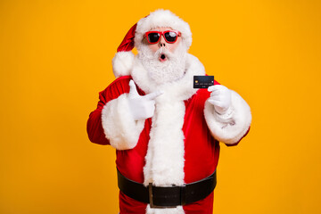 Fototapeta na wymiar Portrait of his he nice attractive fat amazed astonished Santa holding in hand demonstrating bank card safe shopping novelty isolated bright vivid shine vibrant yellow color background