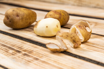 peeled potatoes in the foreground on a wooden background.