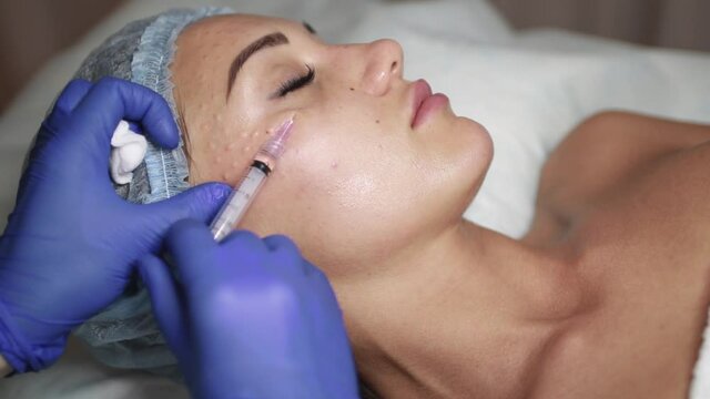 Face mesotherapy procedure in a beauty salon. Beautician doctor makes injections into the skin of the face of a young beautiful woman. Mesotherapy, biorevitalization. Cosmetology.