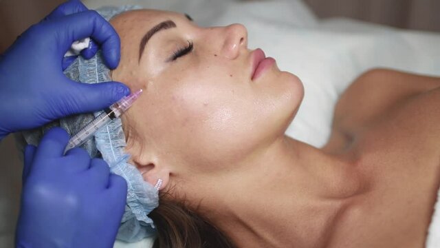 Face mesotherapy procedure in a beauty salon. Beautician doctor makes injections into the skin of the face of a young beautiful woman. Mesotherapy, biorevitalization. Cosmetology.
