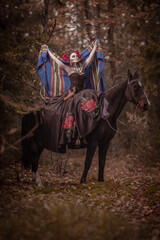 Young woman dressed as mexican symbol of day of the dead posing in forest with horse