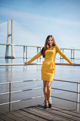 beautiful and slender girl in a yellow dress. photo and view of the big bridge. mysterious look. walking concept. rest and beauty