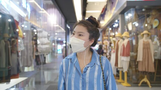 attractive asian female wearing facial mask corona virus protective new normal lifestyle walking shopping in malls supermarket background