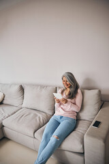 Obraz premium Beautiful pretty female in pink sweater looking to the screen her technology tablet in room indoors