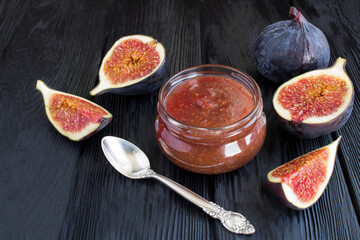Closeup on fig jam in the glass jar on the black wooden background